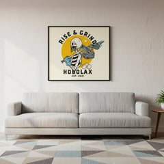 Framed artwork with 'Rise & Grind Hobolax' design above a gray sofa in a living room.