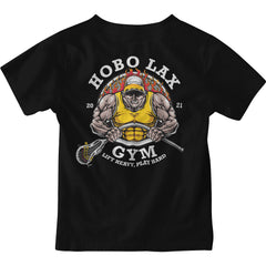 The image showcases the Youth Lift Heavy Tee by Hobo Lax, displaying a striking graphic of a muscular figure wearing a yellow tank top and cap while holding a lacrosse stick. The design includes the text "HOBO LAX GYM" and "Lift Heavy, Play Hard," alongside the year "2021." Fiery flames enhance the boldness and add an extra layer of motivation to this energetic black tee.